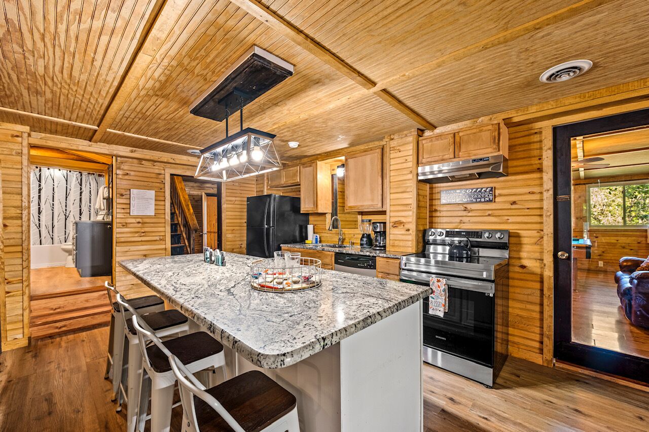 A modern kitchen with wooden walls, a granite countertop, and stainless steel appliances.