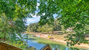 A wooden deck overlooking a calm river, surrounded by lush greenery and trees.