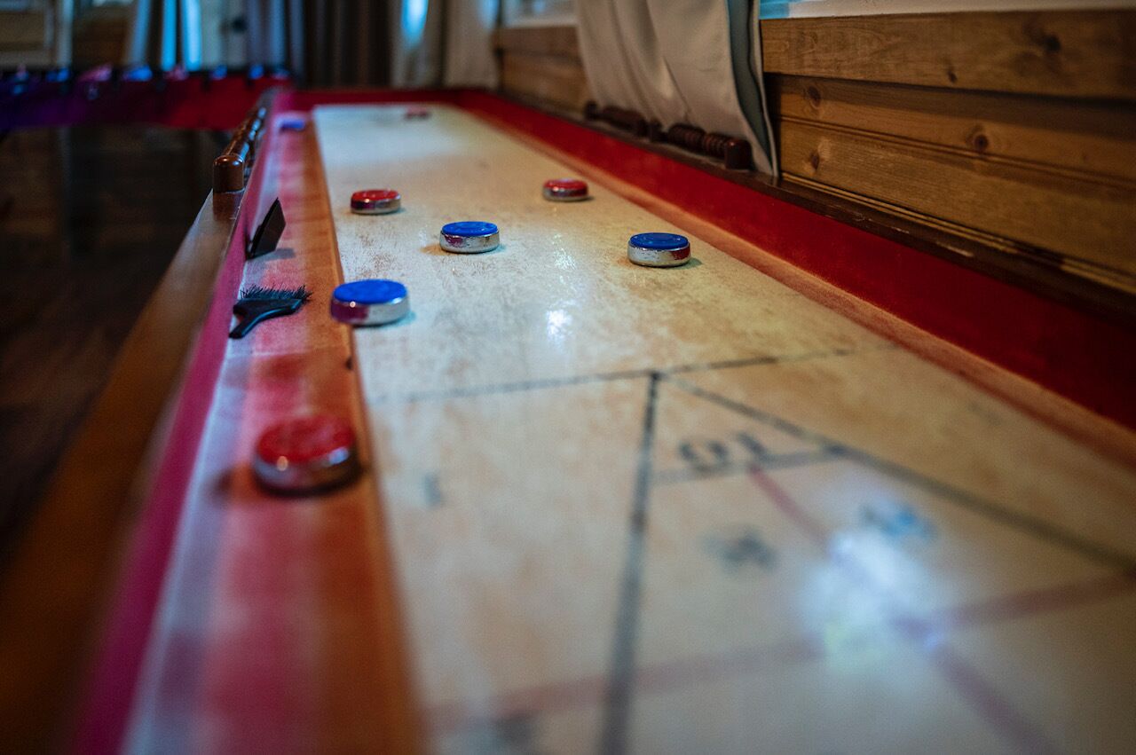 Una mesa de shuffleboard con discos y zona de puntuación.