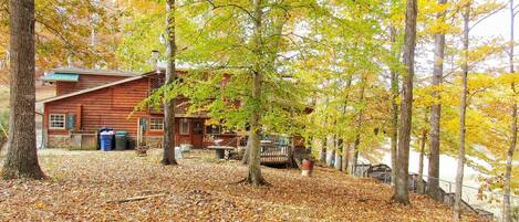 A rustic cabin surrounded by trees with autumn leaves.