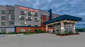 Ein Hampton Inn & Suites Hotel mit moderner Architektur, einem überdachten Eingangsbereich und einem Parkplatz mit Behindertenparkplätzen.