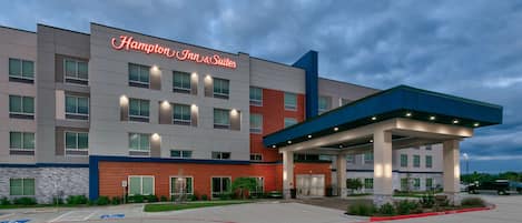 A Hampton Inn & Suites building with a modern design, a covered entrance, and a parking lot with handicapped spaces.