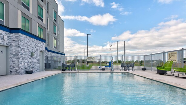 Ein Pool mit Liegestühlen und ein Gebäude mit steinverkleideter Fassade.