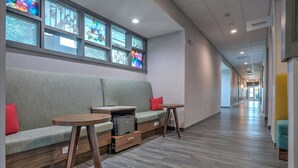 Ein moderner Flur mit einer Sitzecke, inklusive Sofa, zwei kleinen Tischen und einem Drucker.