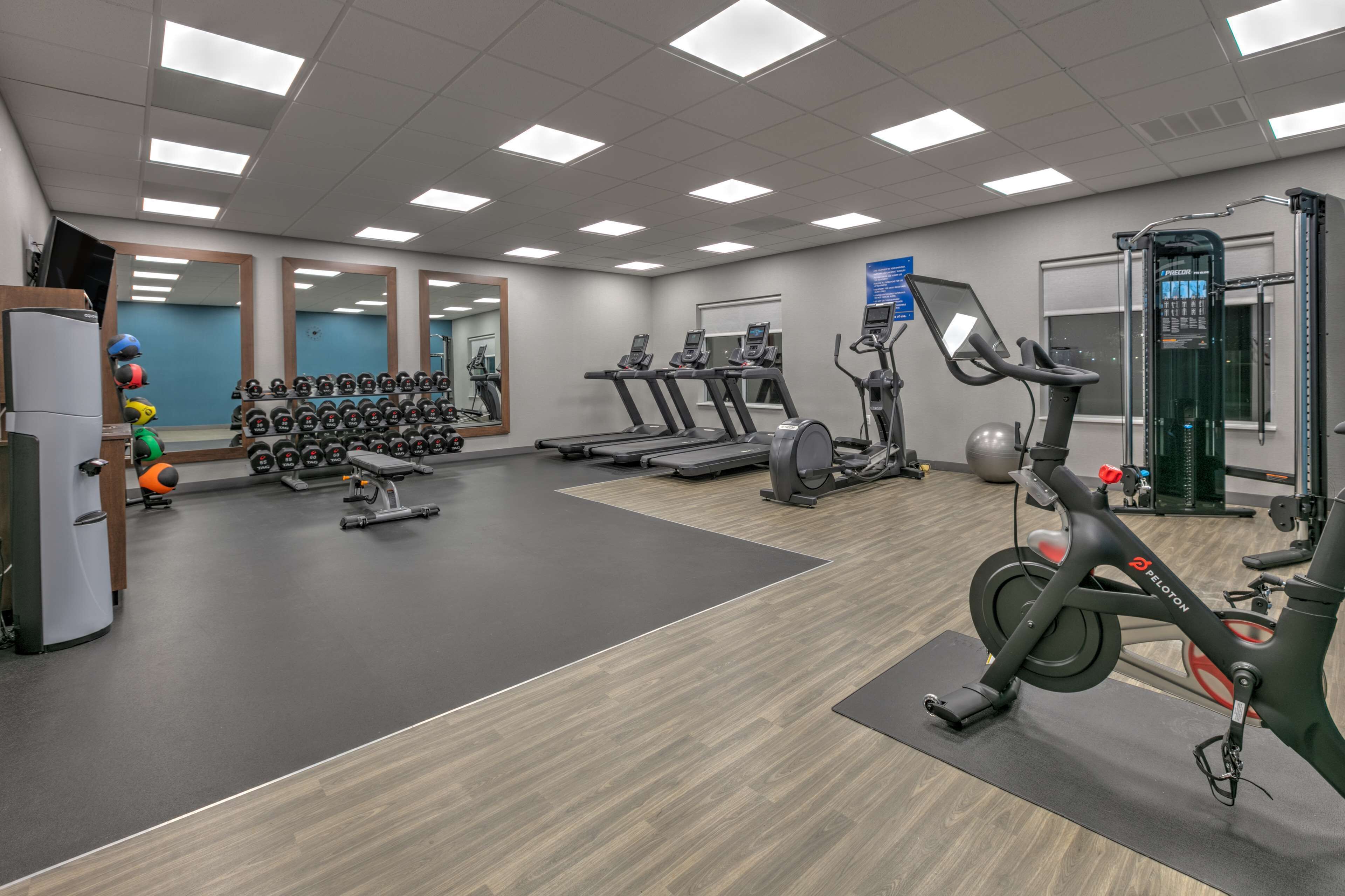 A gym with treadmills, elliptical machines, and weight racks.