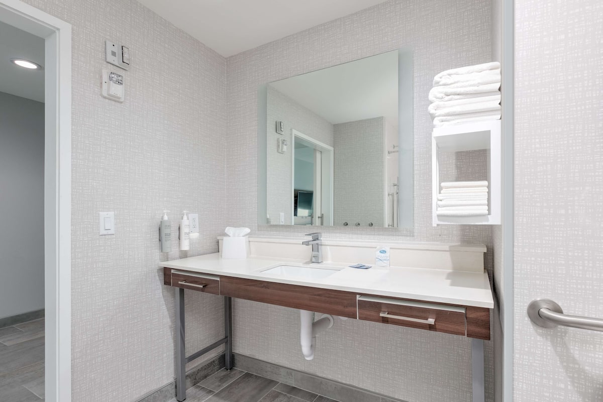 A modern bathroom with a white sink, a mirror, and a towel rack.