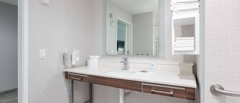 Un baño moderno con un lavamanos blanco, un espejo y un perchero para toallas.