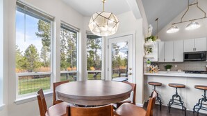 A modern kitchen with white cabinets, a round dining table, and bar stools. - River Front House -20 min to Bend -25 min to Mt Bachelor - Sleeps 12 (Bend)
