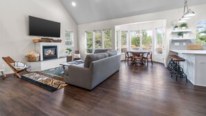 A spacious living area with a fireplace, a sofa, a dining table with chairs, and a kitchen area with bar stools. - River Front House -20 min to Bend -25 min to Mt Bachelor - Sleeps 12 (Bend)