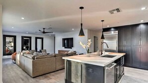 A modern kitchen with a central island, dark cabinetry, and pendant lighting.