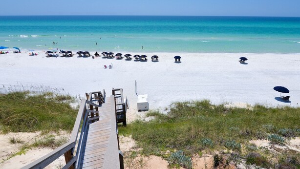 A beach with a wooden boardwalk leading to the shore, clear turquoise water, and beach umbrellas. - 30A Beach Bungalow in Inlet: Steps from Sea, Pool with Golf Cart & Cruiser Bikes (Seacrest)