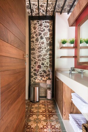 A bathroom with a stone wall, wooden floor, and a modern sink.
