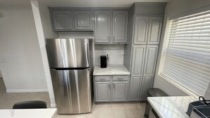 A compact kitchen with a stainless steel refrigerator, white cabinets, and a countertop.