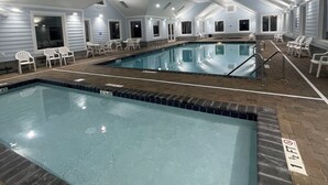 An indoor swimming pool with clear water, surrounded by white chairs and a tiled floor. - Redecorated 3 Bed ,2 Bath ,Sofa bed Outdoor shower Come relax at our beach house (Surfside Beach)