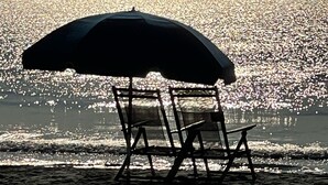 A beach chair under an umbrella facing the ocean. - Redecorated 3 Bed ,2 Bath ,Sofa bed Outdoor shower Come relax at our beach house (Surfside Beach)