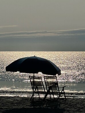A beach chair under an umbrella facing the ocean. - Redecorated 3 Bed ,2 Bath ,Sofa bed Outdoor shower Come relax at our beach house (Surfside Beach)