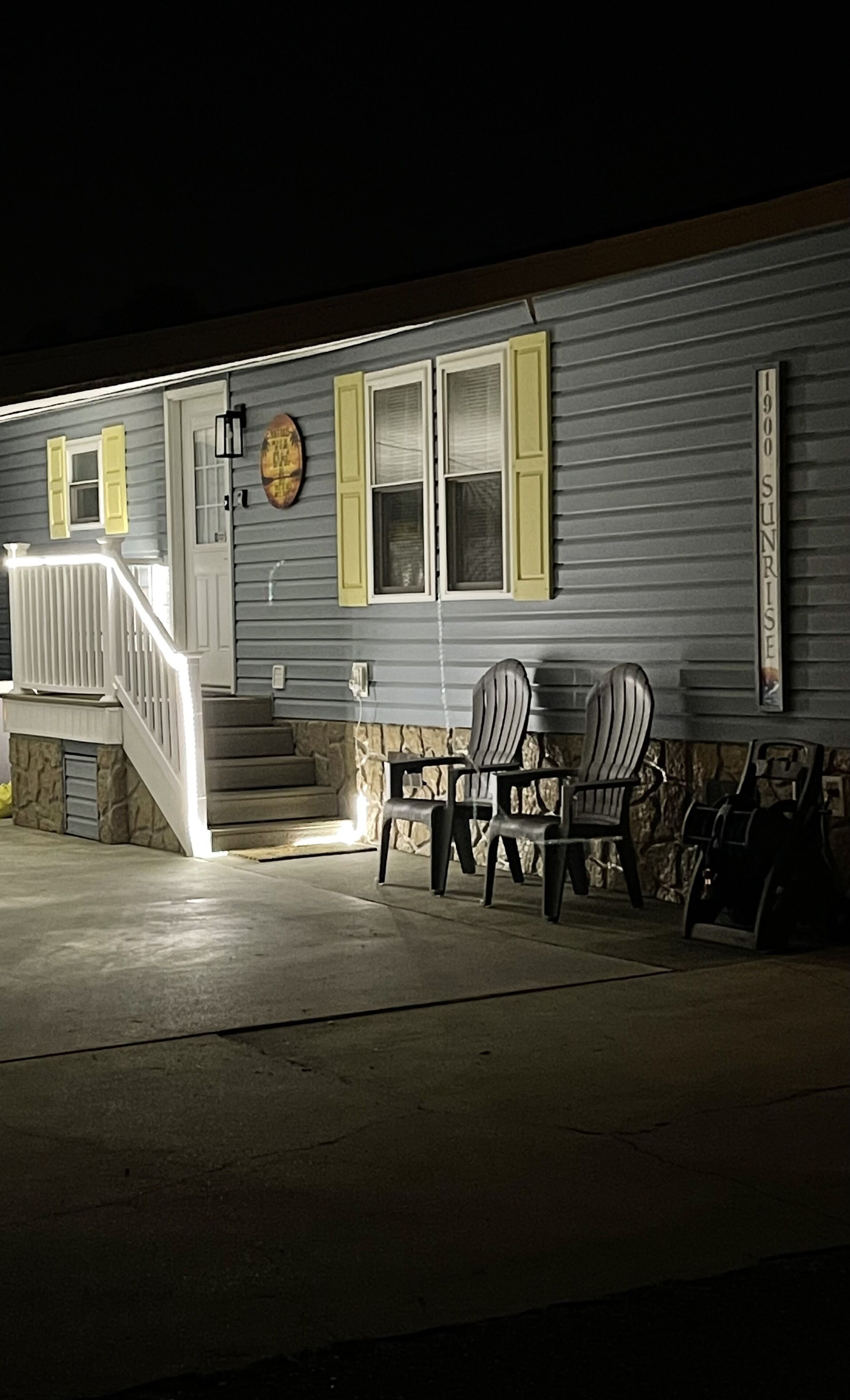 A building with a porch, two chairs, a staircase, and a sign reading "1900 Sunrise".