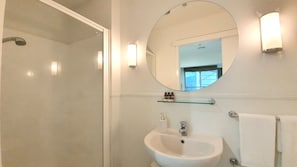 Bathroom features a large mirror, sink, and glass shelf for toiletries.