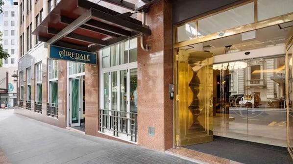Experience the sleek entrance of Airedale Boutique Suites, featuring a large glass door and golden frame.