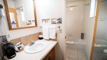 A bathroom with a sink, mirror, and shower.