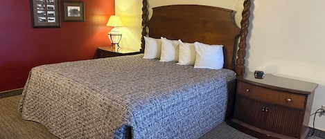 Una habitación de hotel con una cama grande, un cabecero de madera, una mesita de noche y una lámpara.