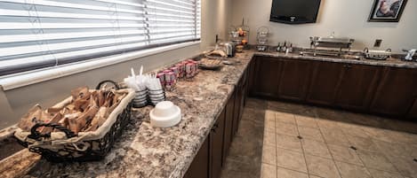 A kitchen with a granite countertop, a sink, a stove, and a window with blinds.
