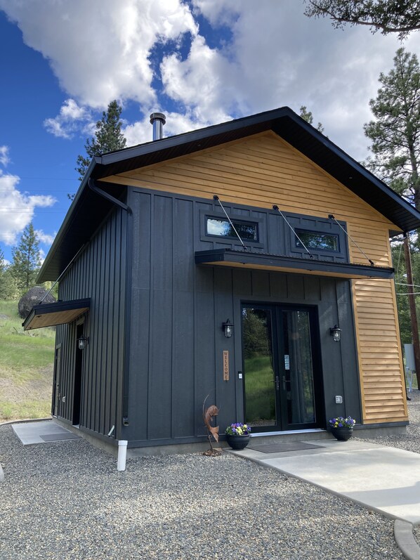 A modern building with a dark facade, a sloped roof, and a welcoming sign. - Relaxing Escape - The Clancy Cottage (Clancy)