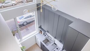 A modern kitchen with grey cabinets, a stainless steel sink, and a window overlooking a street.