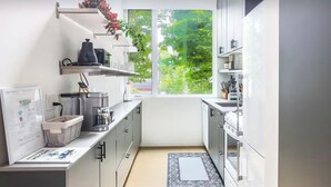 A modern kitchen with white cabinets, a built-in stove, and a window overlooking greenery.