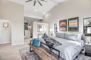 A spacious bedroom with a large bed, a bench, and artwork on the walls.
