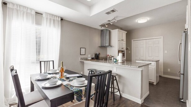 A modern kitchen with a central island, white cabinetry, and a dining area with a table set for four. - •The Gem•Arcade•Covered Parking•Pets•Central! (Euless)