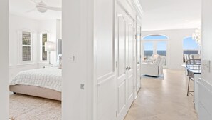 Ein geräumiges Schlafzimmer mit einem großen Bett, einem Deckenventilator und Meerblick durch ein Fenster.