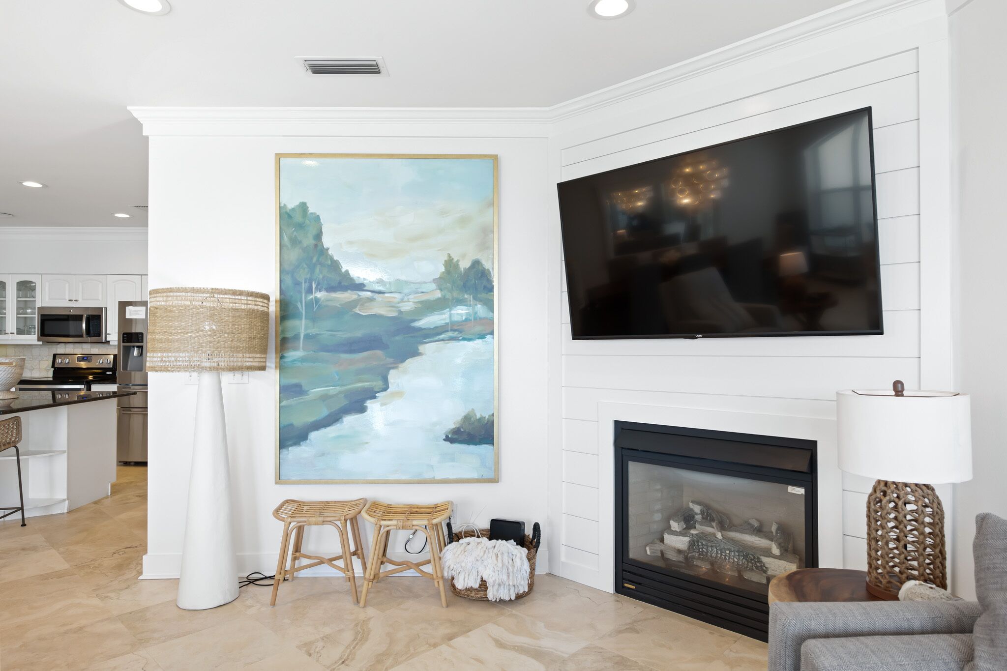 Een moderne woonkamer met een open haard, een groot schilderij en een flatscreen televisie.