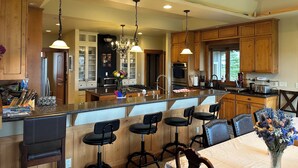 A spacious kitchen with wooden cabinets, a central island with bar stools, and pendant lighting.