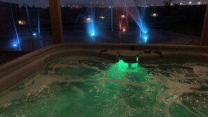 A hot tub with water jets and a view of a cityscape at night. - Fun 4 bedroom house w/ splash pad, near City Center and Saguaro National Forest (Tucson)