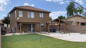 A two-story house with a patio, a covered outdoor seating area, and a well-maintained lawn. - Fun 4 bedroom house w/ splash pad, near City Center and Saguaro National Forest (Tucson)