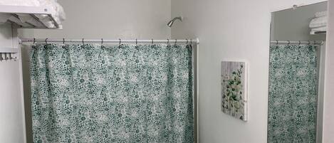 A bathroom with a shower curtain, a toilet, a towel rack, and a mirror.