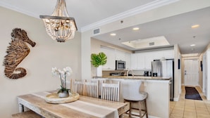 A modern kitchen with white cabinets, stainless steel appliances, and a central island. - Seawind 1005 | Beautiful condo with perfect beach view and walk to dine, shop, more! (Gulf Shores)