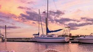A boat docked at a marina with a sunset in the background. - Sunkissed cottage, heated pools, club house, game room, 15 mins to local beaches (Arundel)