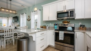 A modern kitchen with white cabinetry, stainless steel appliances, and a granite countertop. - Sunkissed cottage, heated pools, club house, game room, 15 mins to local beaches (Arundel)