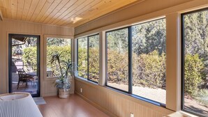 A room with large windows, wooden ceiling, and a potted plant.