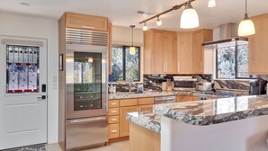 A modern kitchen with wooden cabinets, stainless steel appliances, granite countertops, and pendant lighting.
