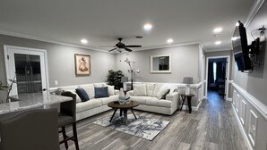 Una sala de estar moderna con un sofá blanco, una mesa de centro y una zona de comedor con barra.