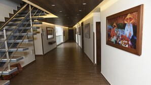 A hallway with a staircase, wooden flooring, and a painting on the wall. - Hotel Kai Soledad (Soledad)