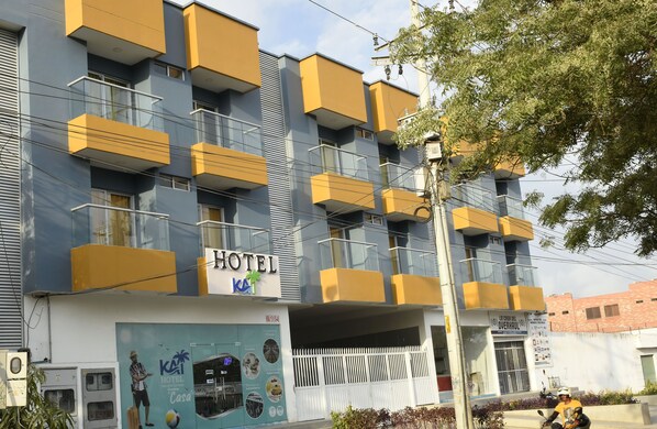 Un hotel de varios pisos con balcones, un cartel que dice "HOTEL KAI" y una entrada visible.