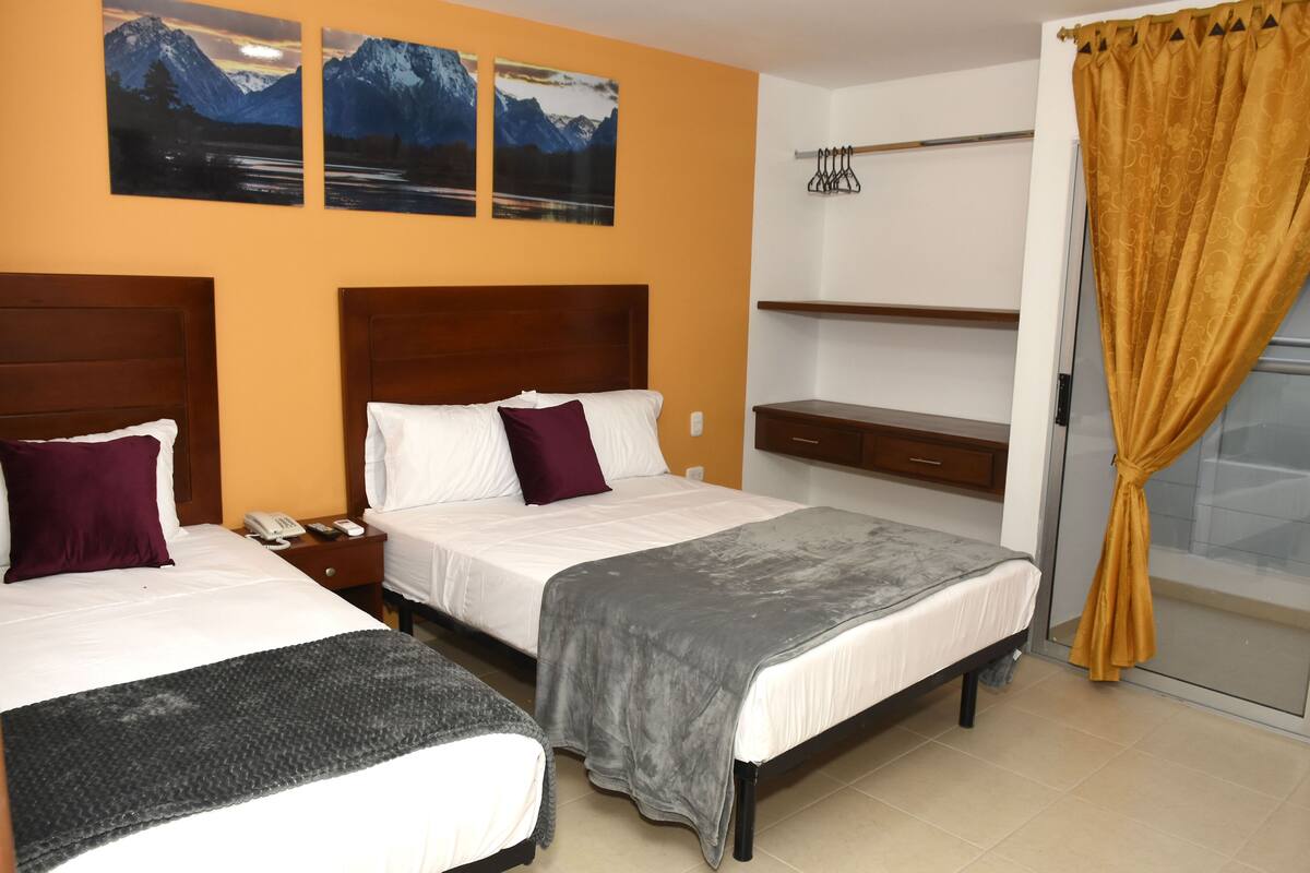 A hotel room with two beds, a nightstand, a desk, a chair, a wardrobe, and a window with curtains.