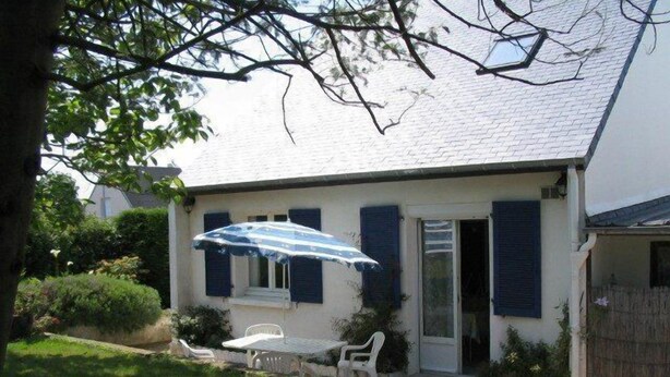 A house with a covered patio, a small table, and two chairs.