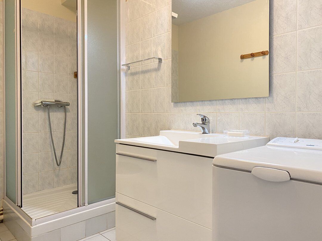 A bathroom with a glass-enclosed shower, a sink, and a mirror.