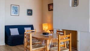 Een gezellige woonkamer met een ronde houten eettafel, een blauwe bank en een open haard.