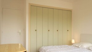 Een slaapkamer met een bed, een nachtkastje en een garderobe met vijf deuren.